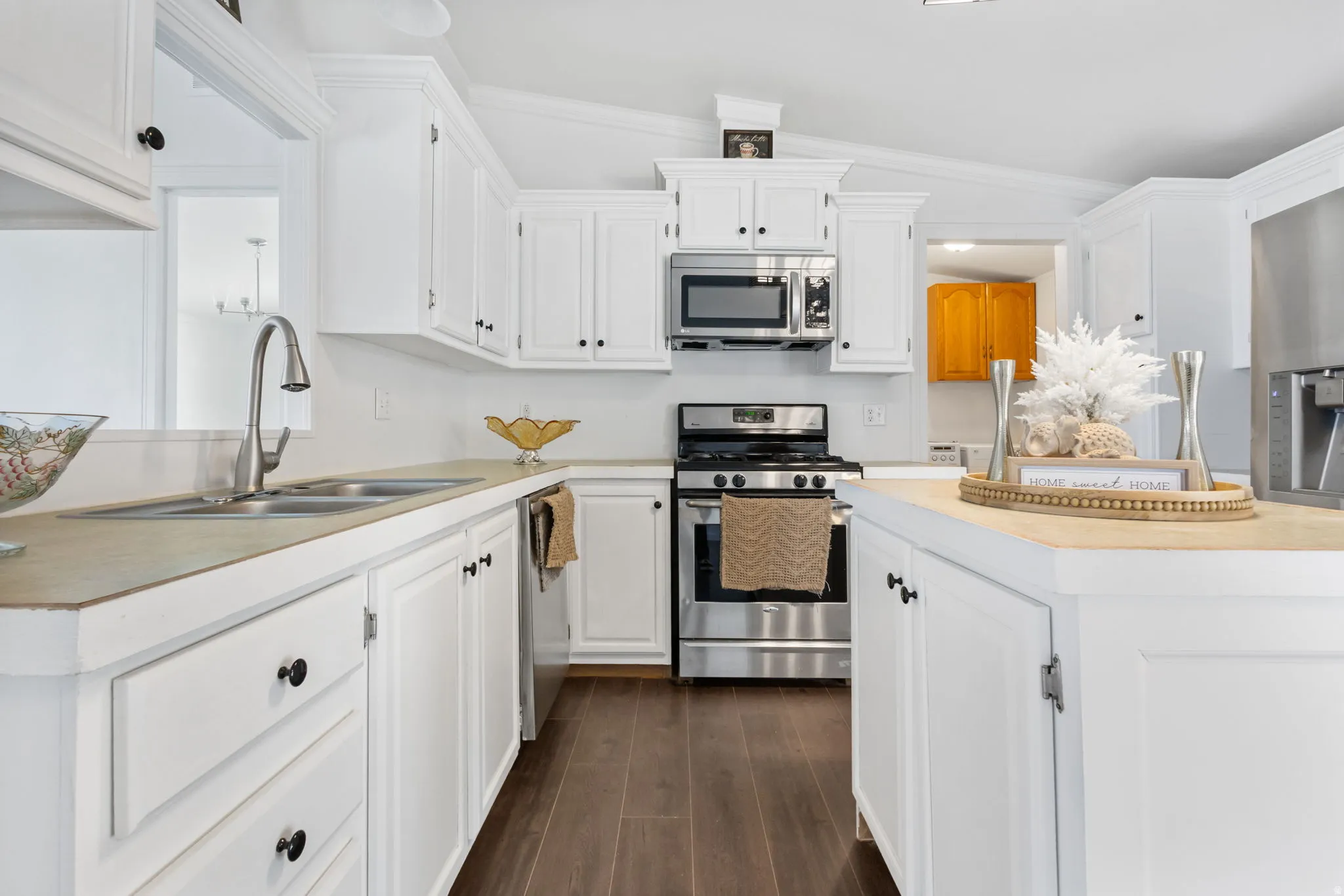 Kitchen featuring stainless steel appliances, light countertops, white cabinetry, and crown molding