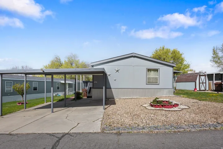 View of front facade with a storage shed, a carport, and concrete driveway