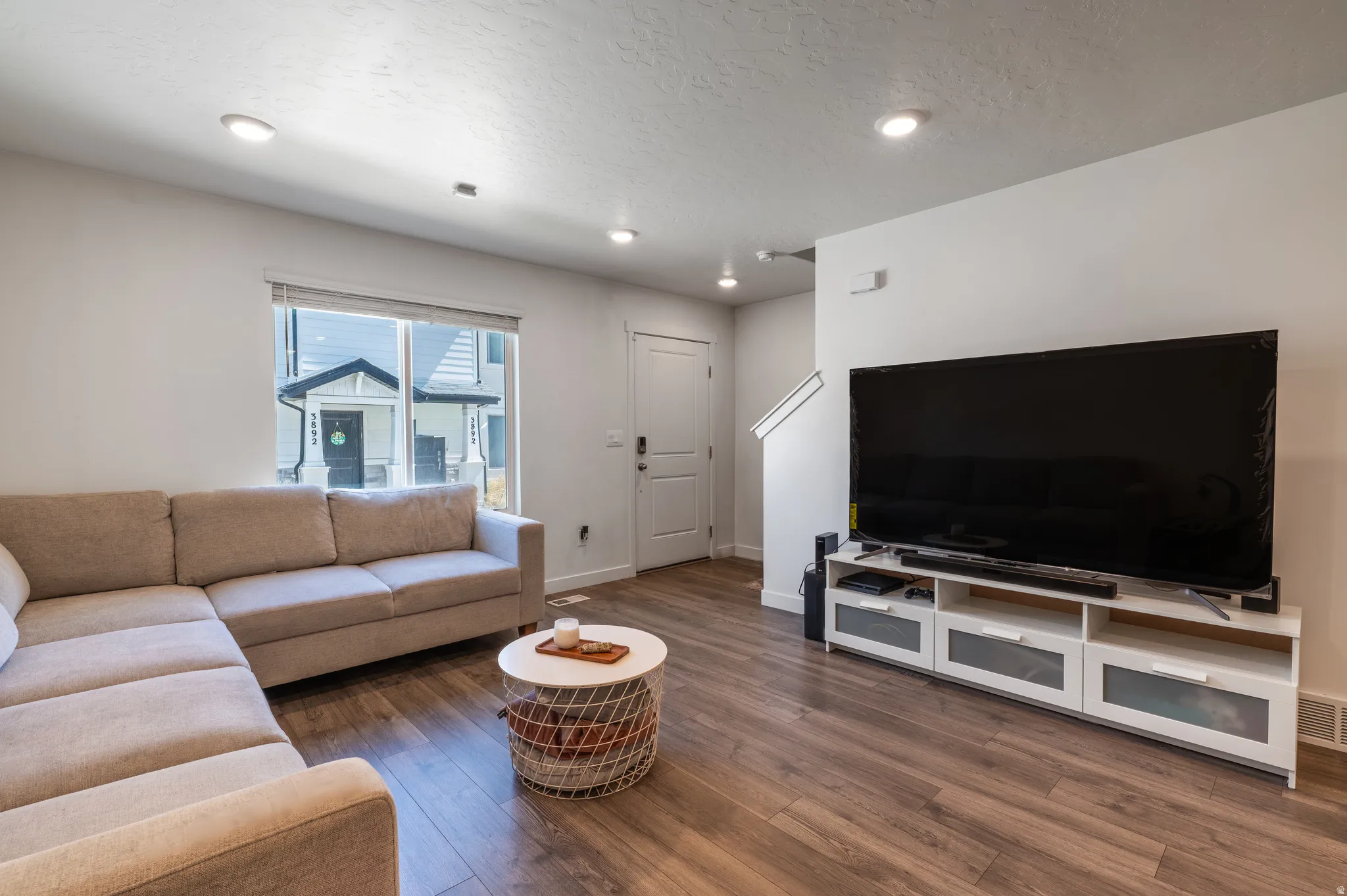 Living room with dark wood-style floors, a textured ceiling, and recessed lighting