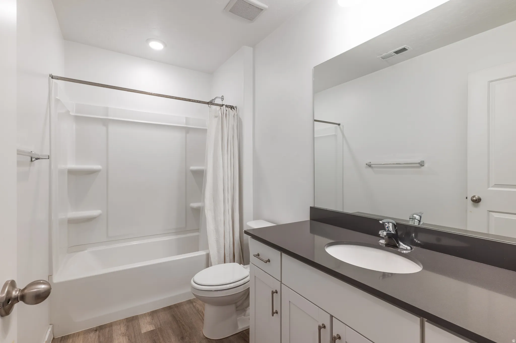Bathroom featuring light wood-type flooring, vanity, and shower / bath combo
