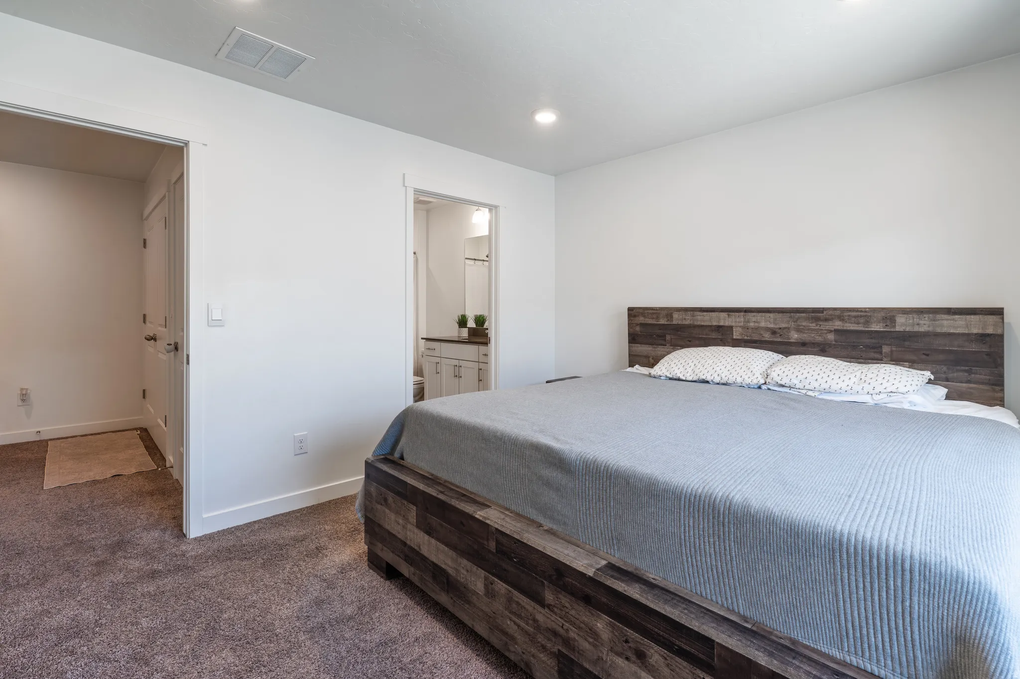 Bedroom with dark carpet, ensuite bathroom, and recessed lighting