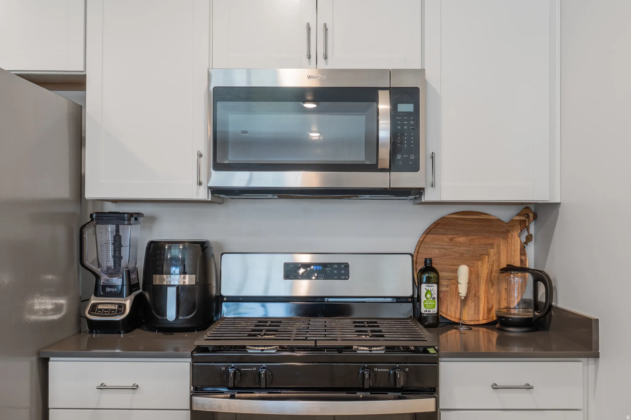 Kitchen featuring stainless steel appliances, white cabinets, and dark countertops