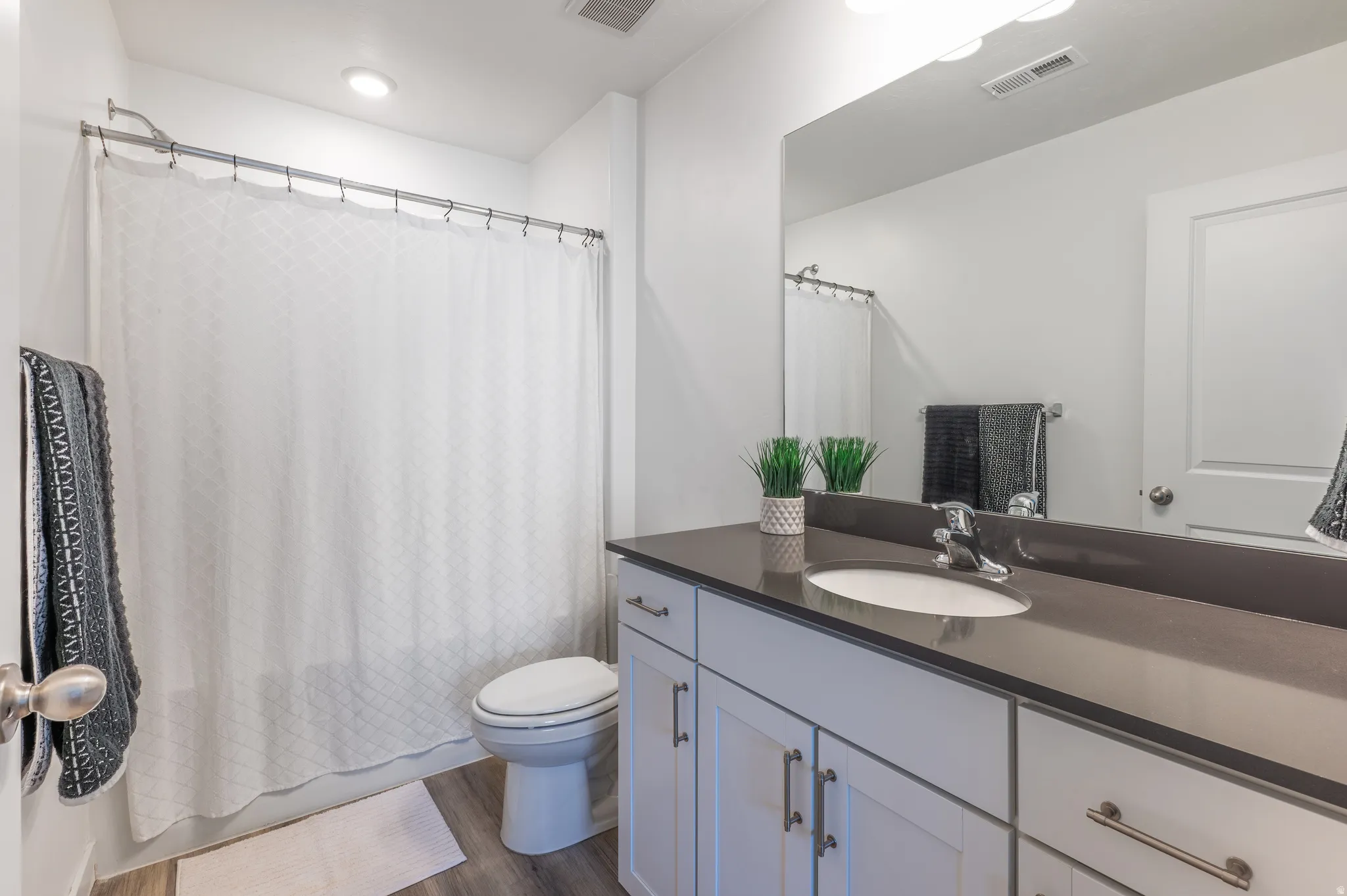 Full bath featuring vanity, dark wood finished floors, and shower / tub combo with curtain