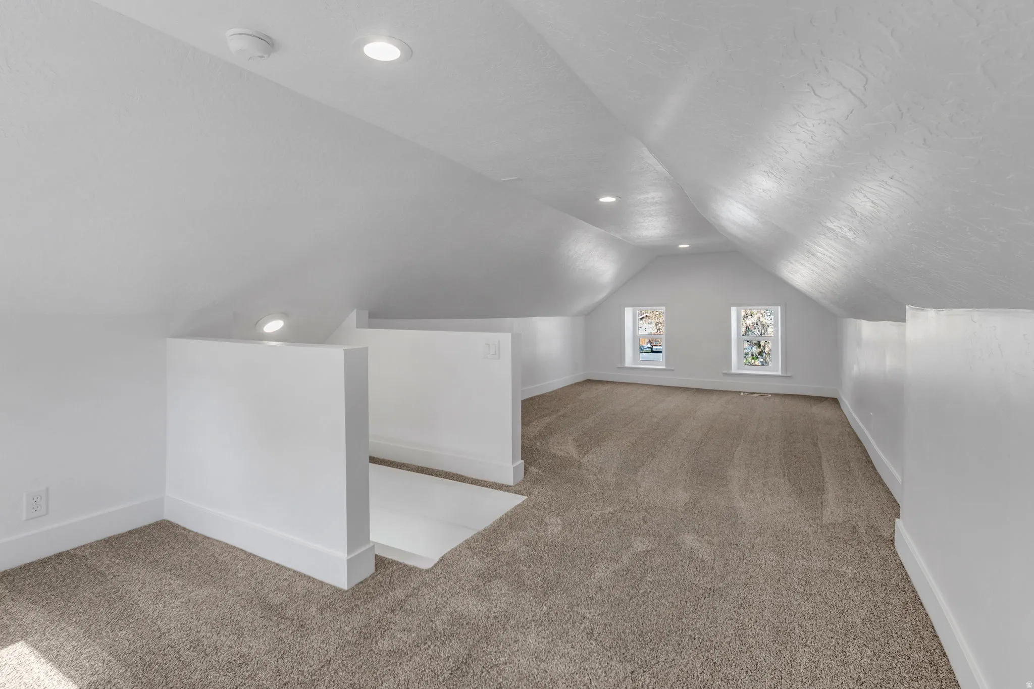 Loft with light colored carpet and recessed lighting
