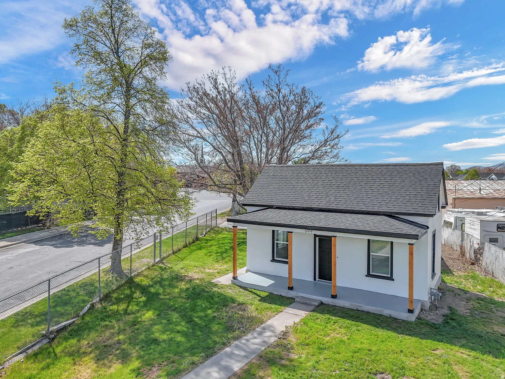 View of front of property featuring a shingled roof, a porch, and stucco siding.