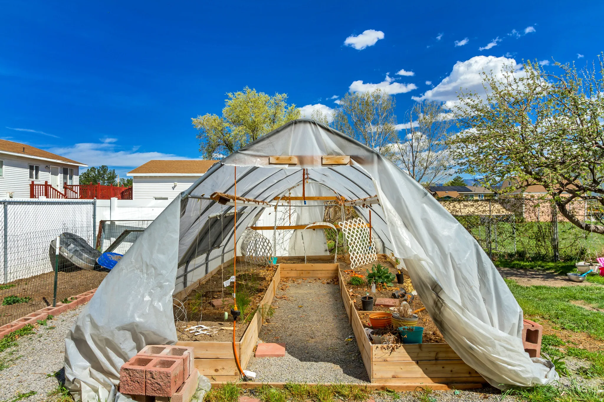 View of greenhouse with a vegetable garden and a fenced backyard