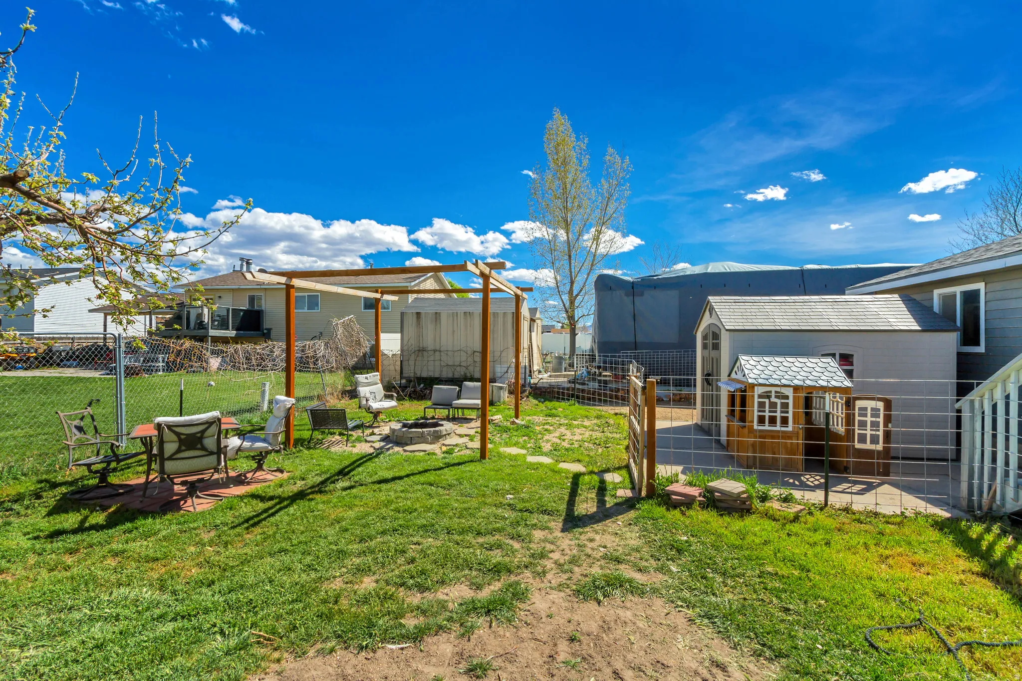 Fenced backyard with an outdoor fire pit, a patio area, and an outbuilding