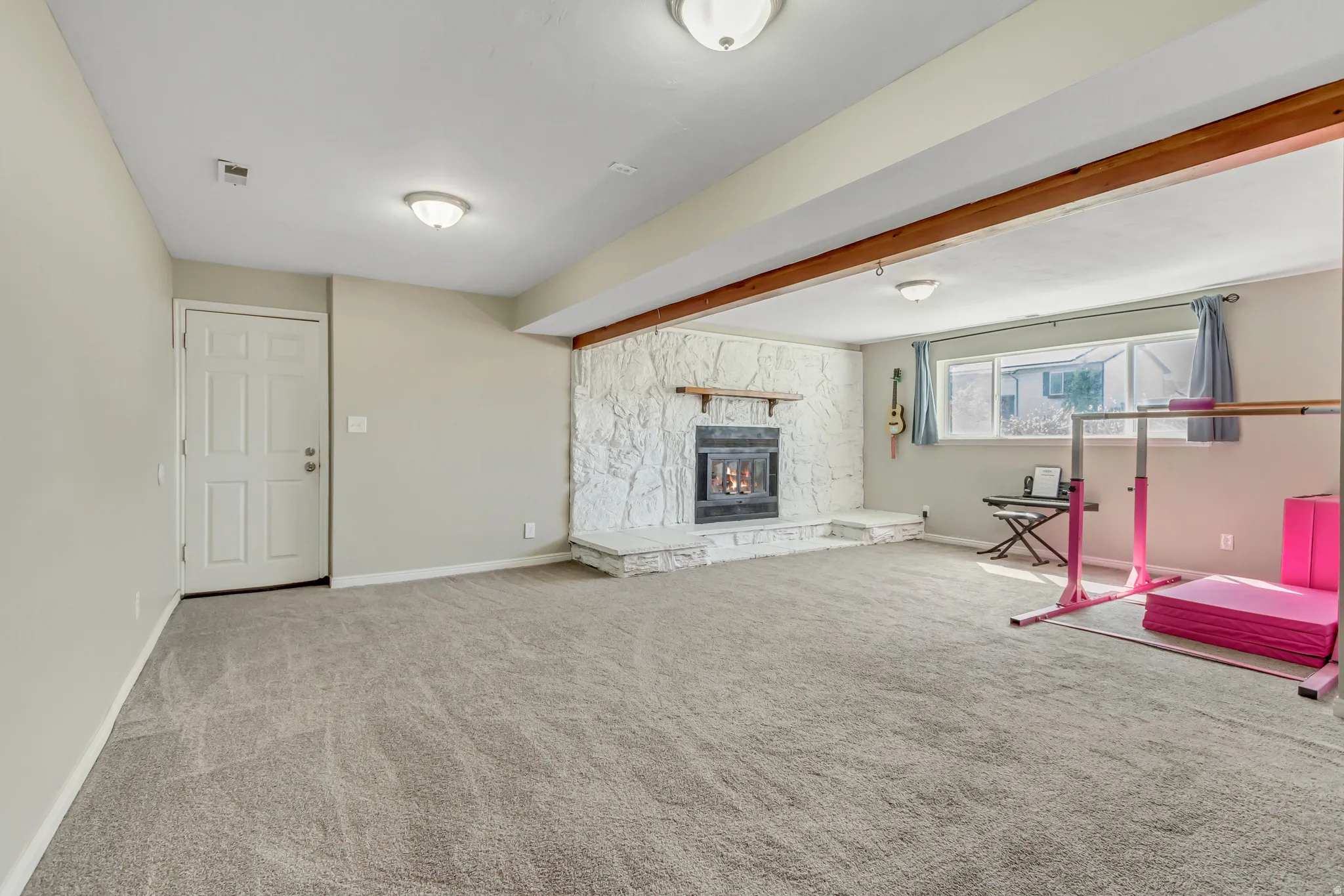 Unfurnished living room featuring carpet floors and a stone fireplace