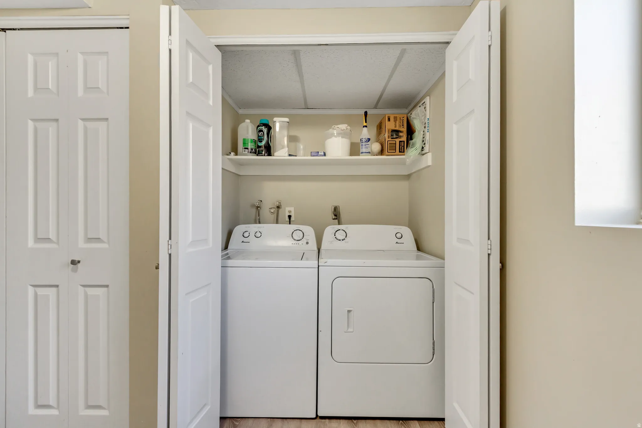 Laundry area with independent washer and dryer and light wood-type flooring