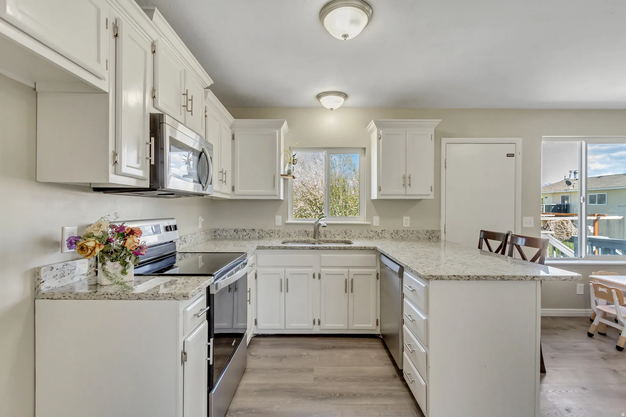Kitchen featuring a peninsula, stainless steel appliances, a kitchen breakfast bar, and white cabinetry