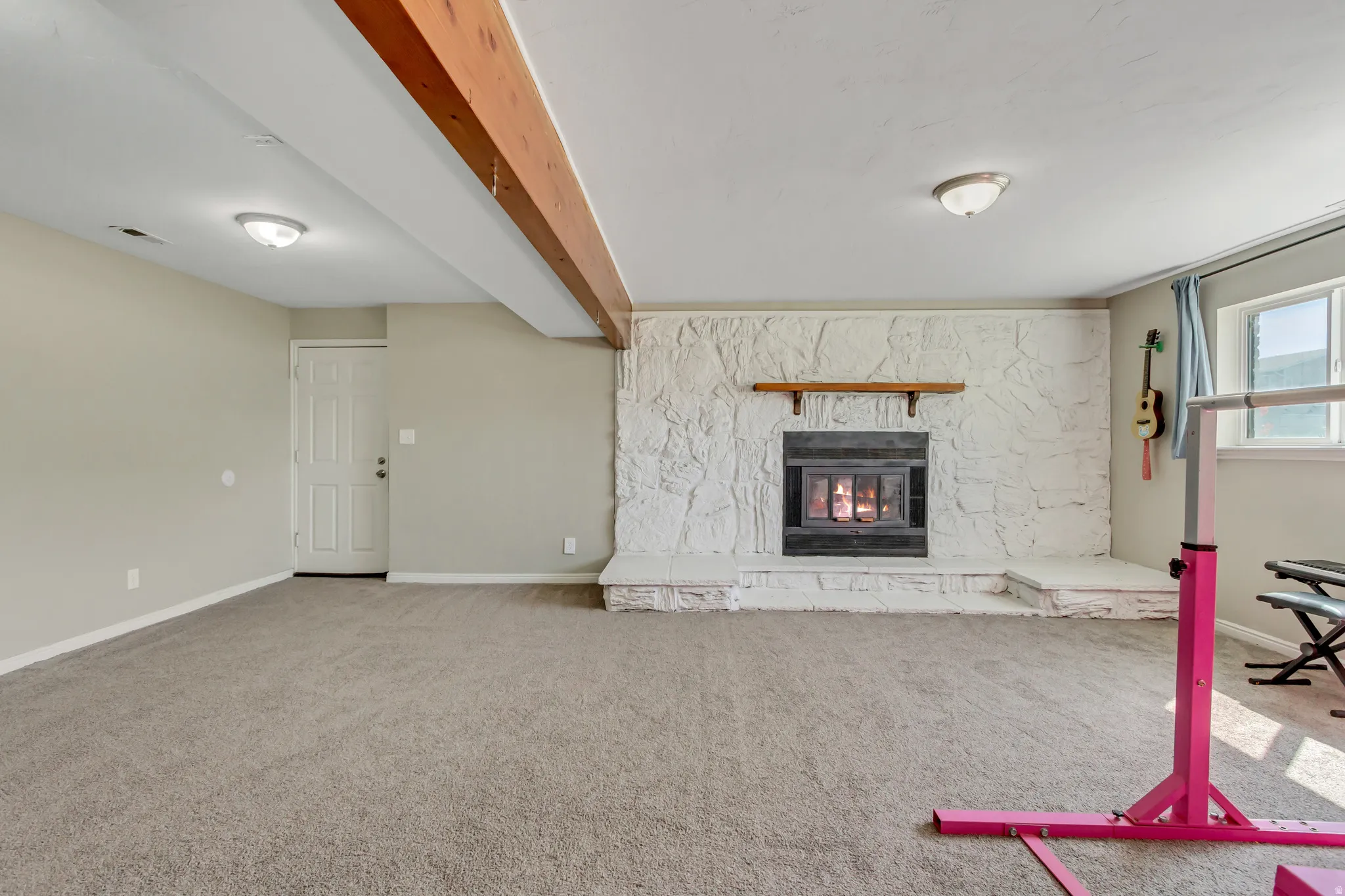 Unfurnished living room with a fireplace, beamed ceiling, and carpet flooring