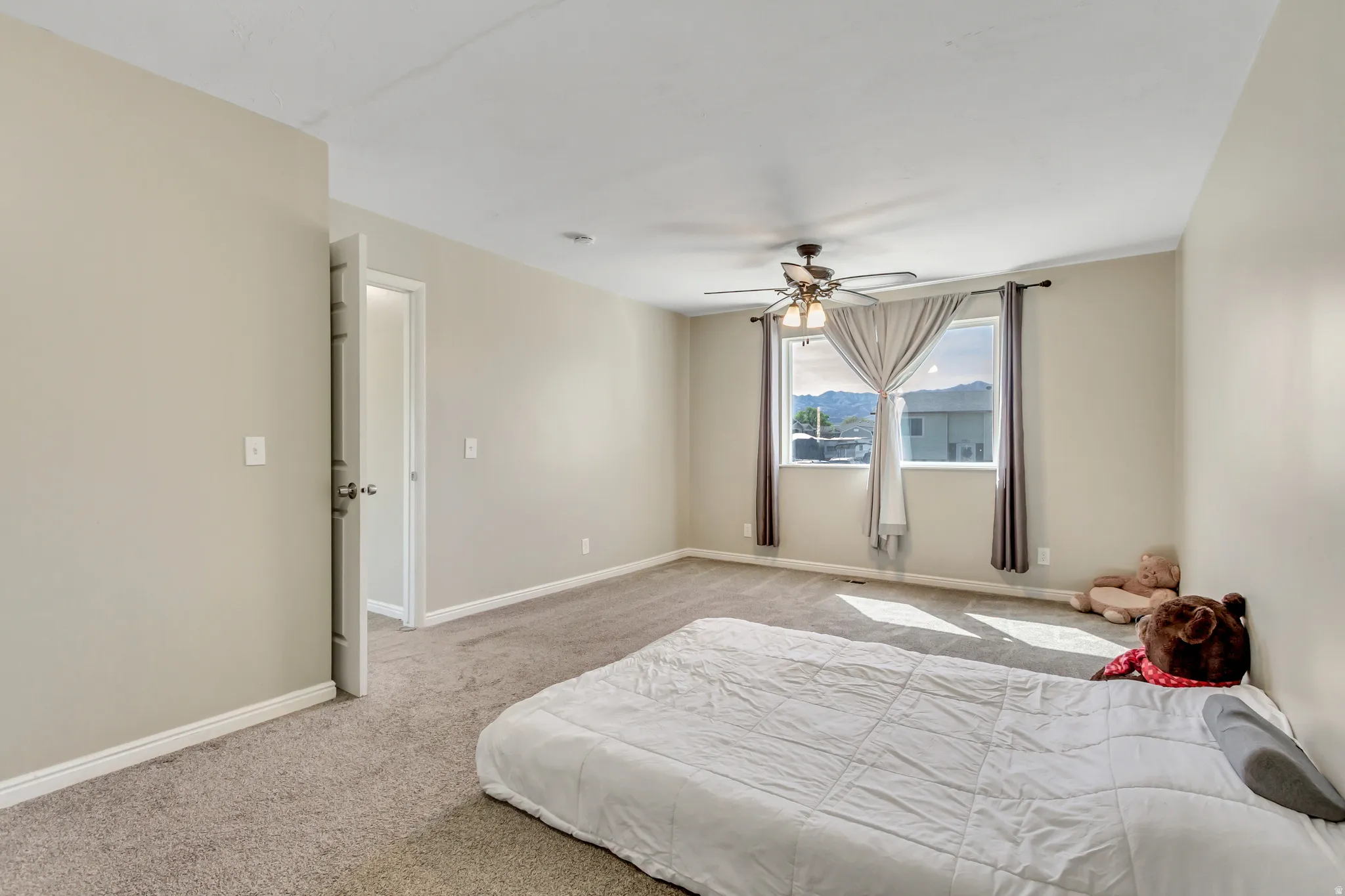 Bedroom with light carpet, ceiling fan, and a mountain view