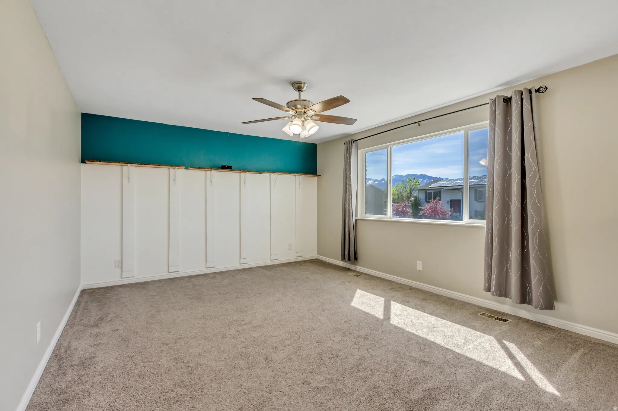 Spare room with a mountain view, light colored carpet, and ceiling fan