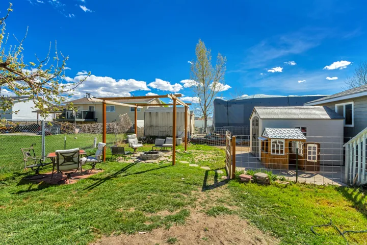 Fenced backyard with an outdoor fire pit, a patio area, and an outbuilding