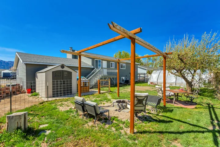 Fenced backyard featuring a fire pit, a patio area, and a shed