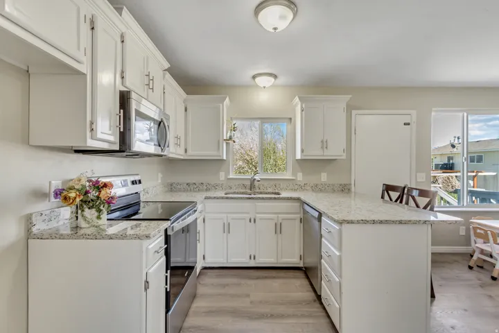 Kitchen featuring a peninsula, stainless steel appliances, a kitchen breakfast bar, and white cabinetry