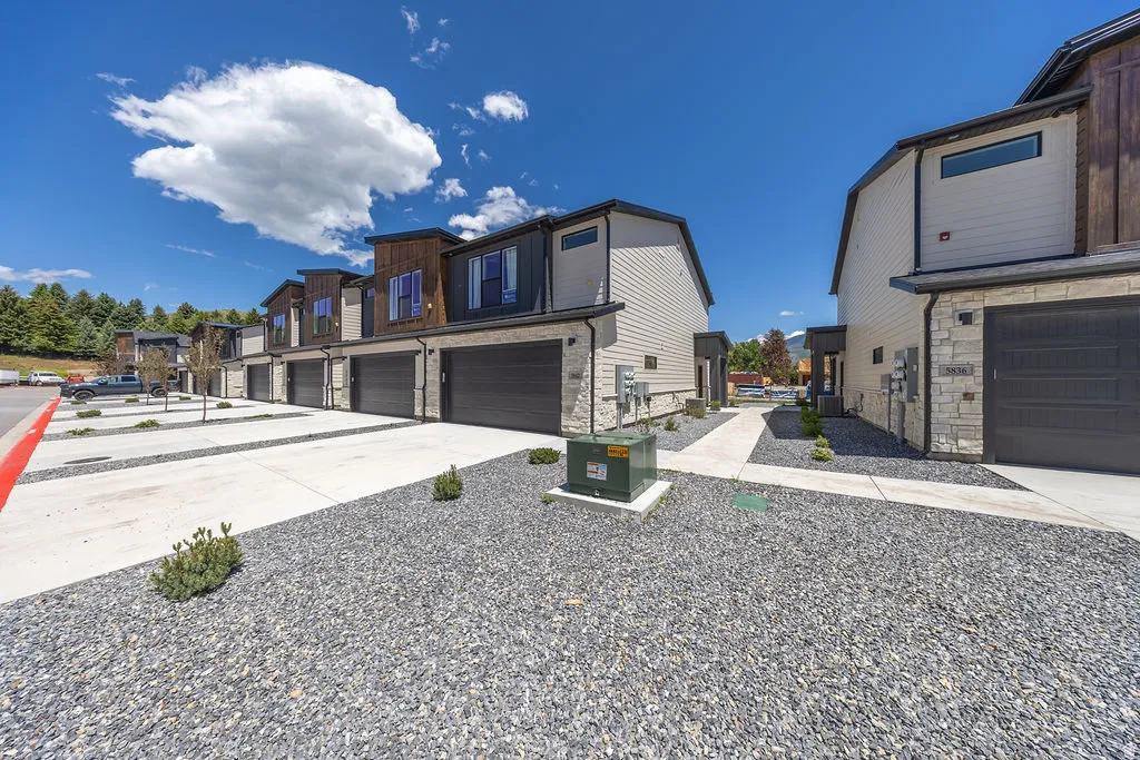 Modern townhome exteriors featuring wood-look siding accents, light-toned horizontal siding, and stone veneer bases