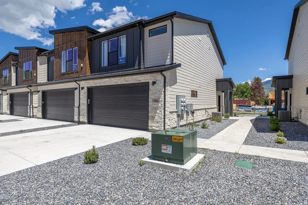 Modern townhome exterior featuring stone veneer and vertical wood siding accents