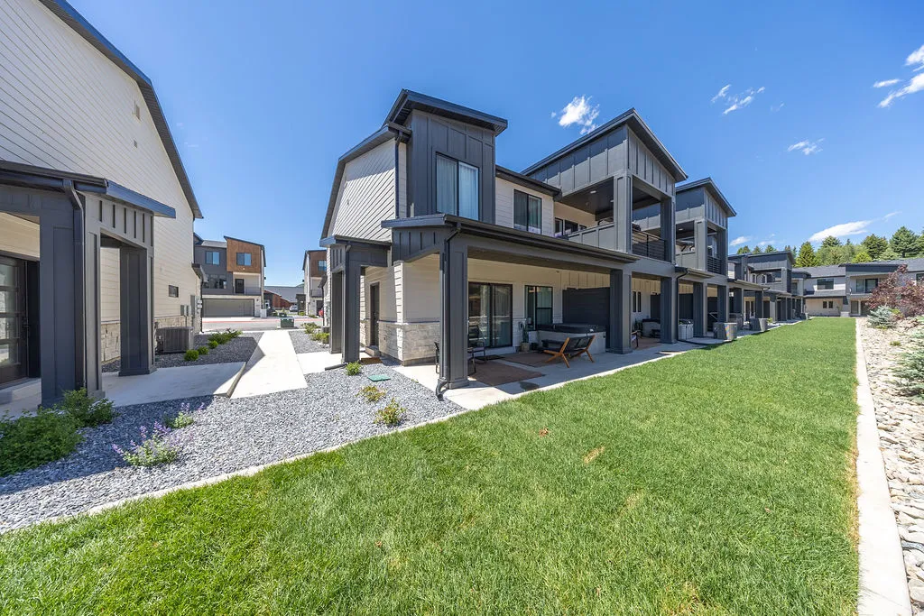 Contemporary multi-story residences featuring covered patios, private balconies, and an expansive grassy area