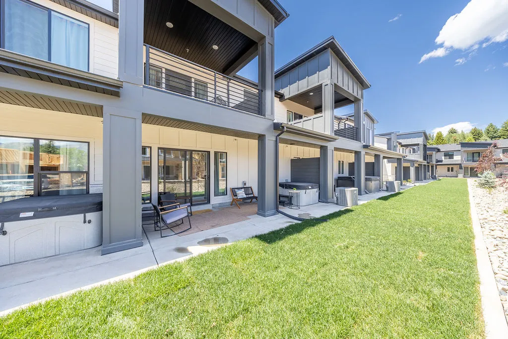 Contemporary townhome exterior featuring an expansive green lawn and a private concrete patio