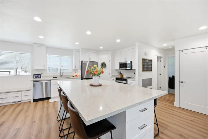 Kitchen with a breakfast bar area, light wood-style floors, white cabinetry, and recessed lighting