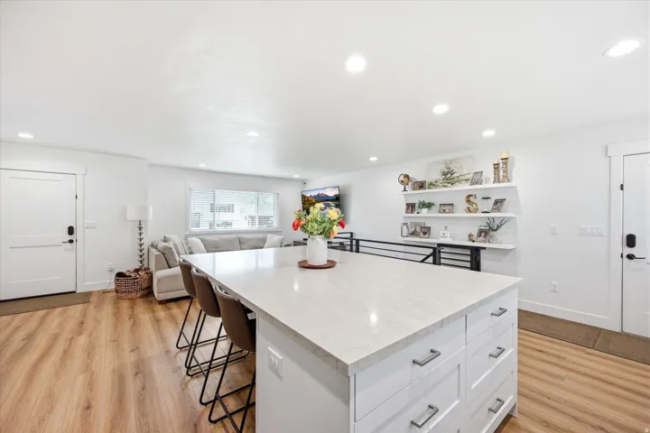Kitchen featuring a breakfast bar area, a center island, light wood-style floors, open floor plan, and white cabinetry