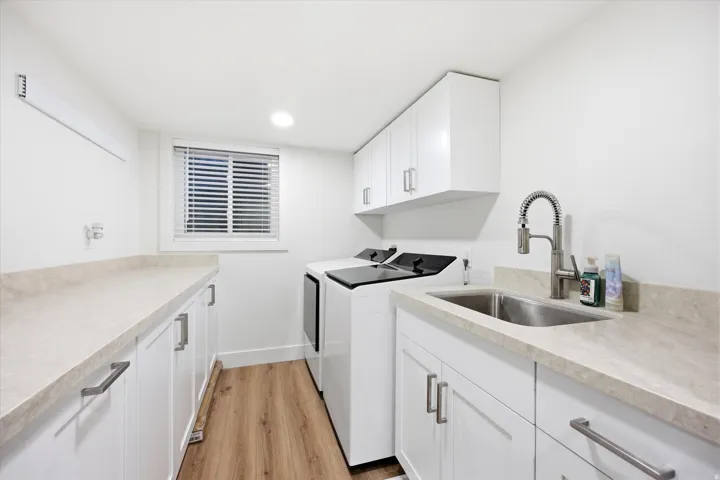 Laundry room with light wood-type flooring, cabinet space, washer and clothes dryer, and recessed lighting