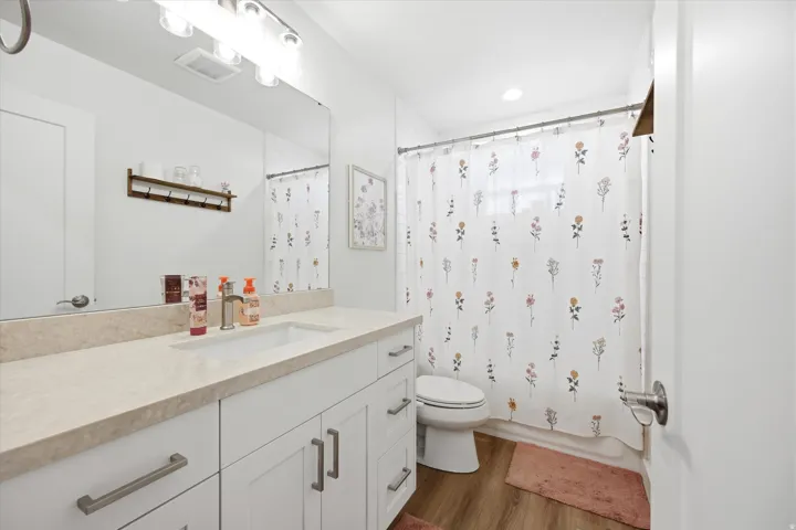 Full bathroom with vanity, shower / tub combo, and dark wood finished floors