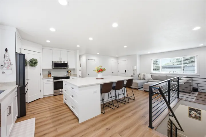 Kitchen with open floor plan, a kitchen island, stainless steel appliances, a kitchen bar, and recessed lighting