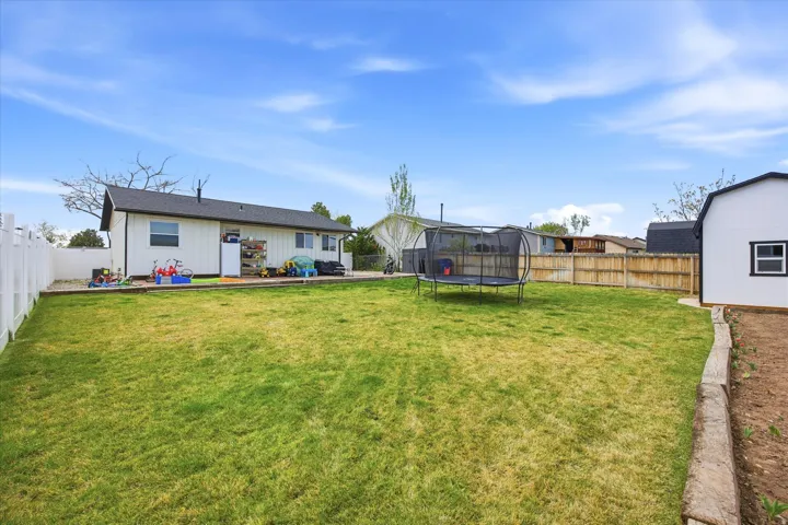 Back of property featuring a fenced backyard, a trampoline, and board and batten siding