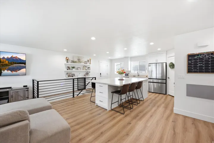 Kitchen featuring a kitchen breakfast bar, a kitchen island, freestanding refrigerator, white cabinetry, and light wood-style floors
