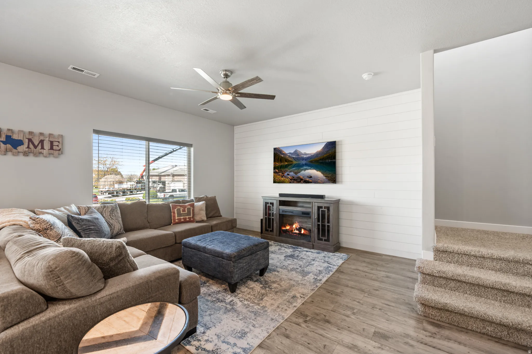Living area with a ceiling fan, LVP floors, wooden accent wall.