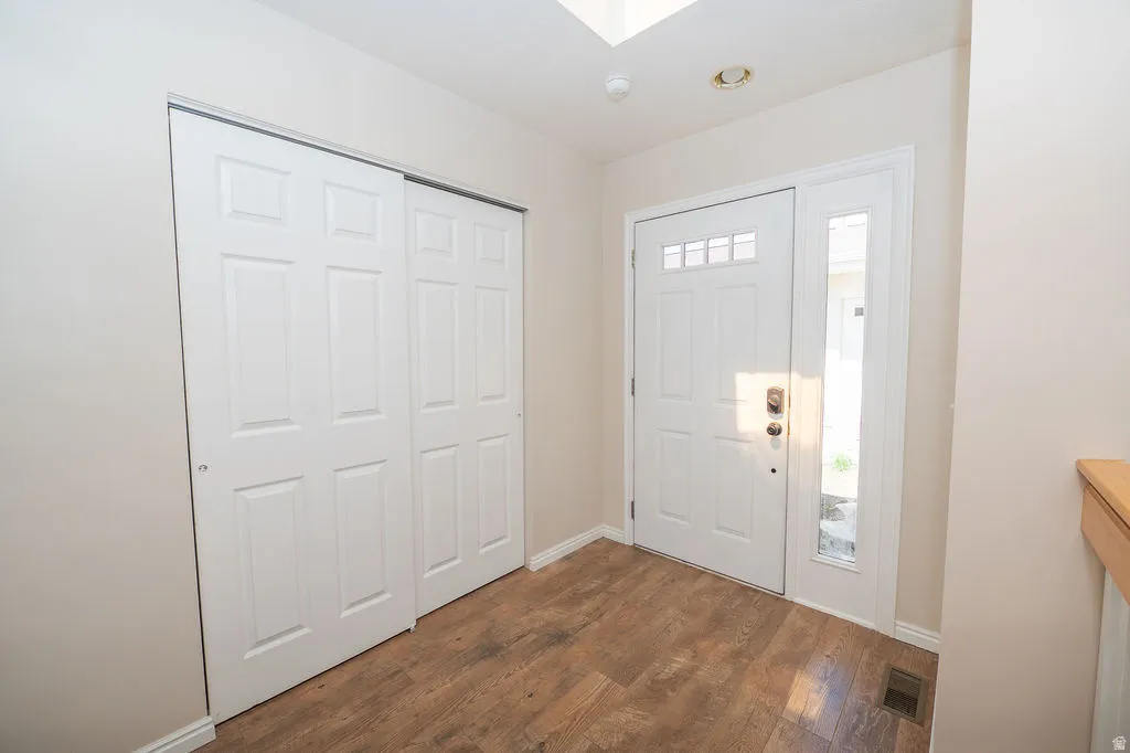 Entrance foyer with LVP flooring and a large coat closet. Above the entry is a skylight.