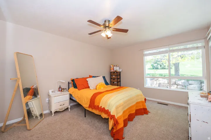 East bedroom with new carpet, big windows, and a ceiling fan.