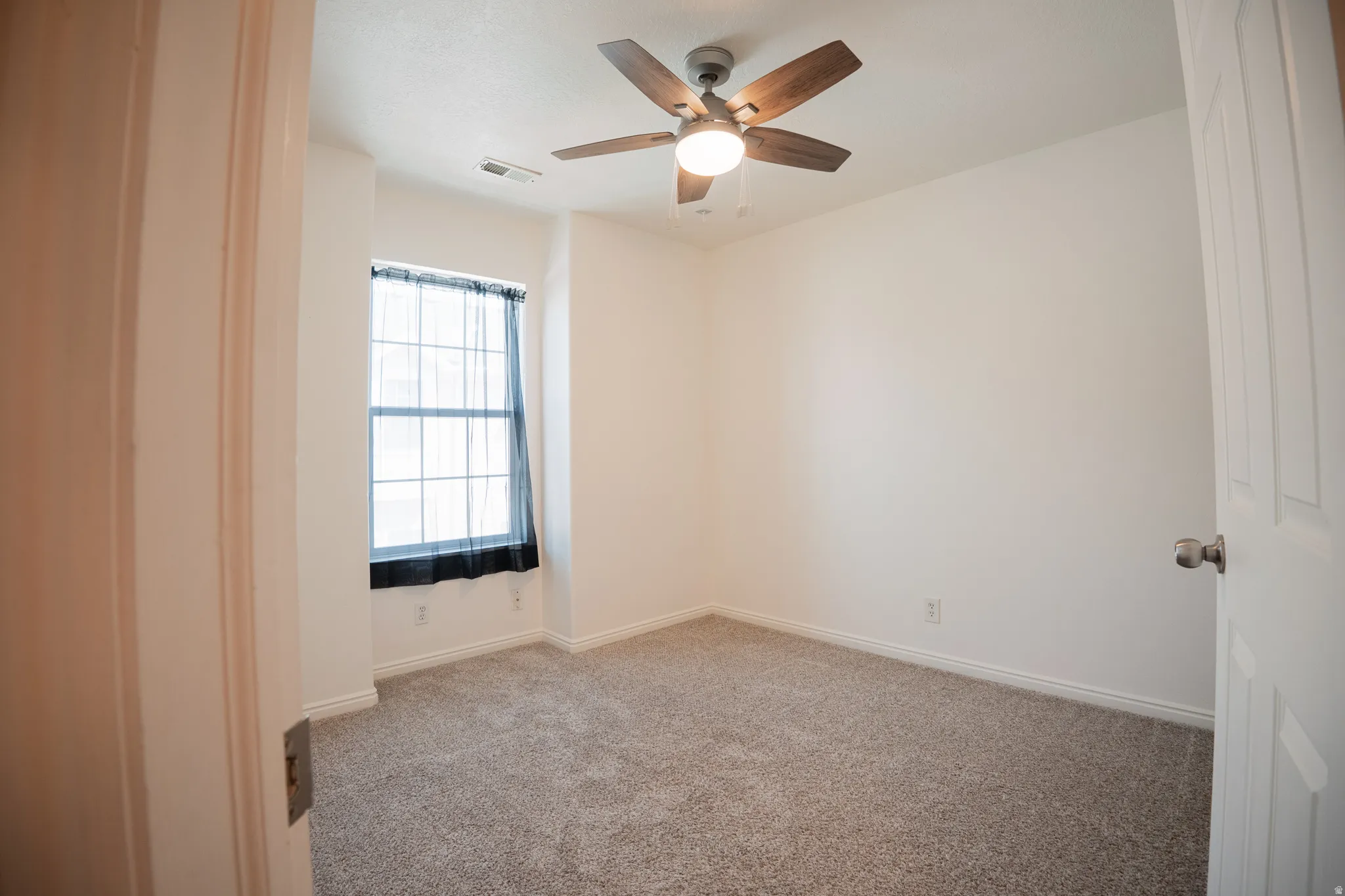 Unfurnished room with light colored carpet and ceiling fan