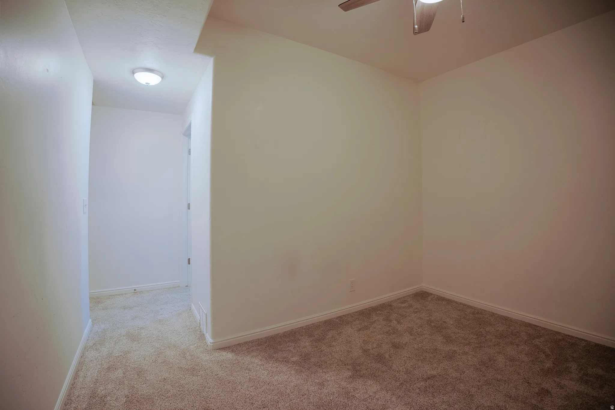 Spare room featuring light carpet and ceiling fan