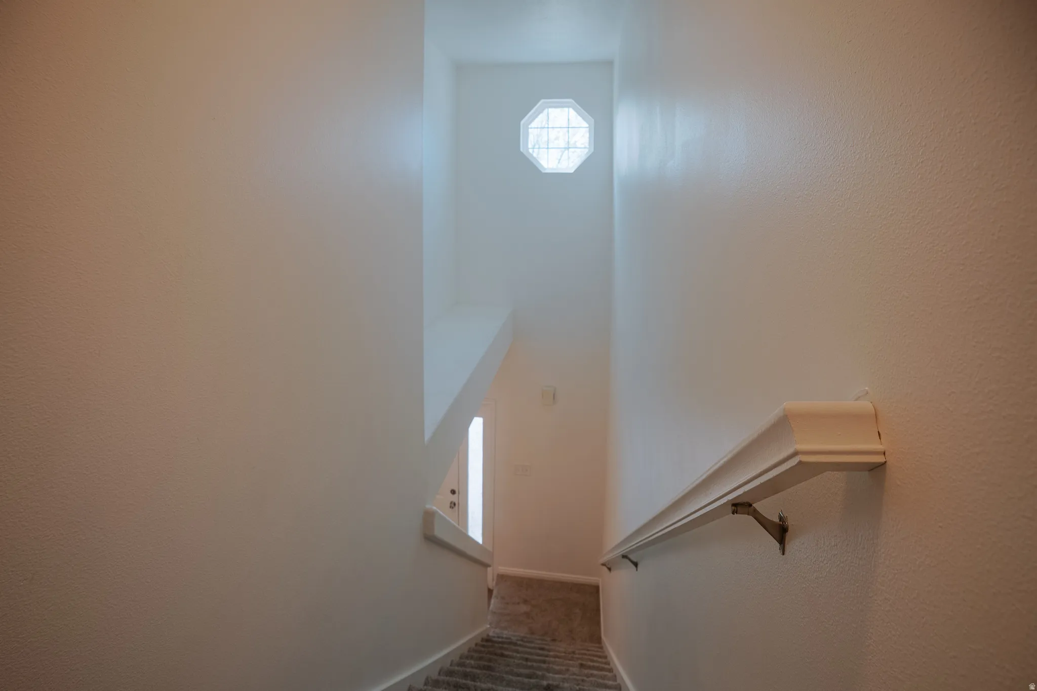 Staircase with carpet flooring and a textured wall