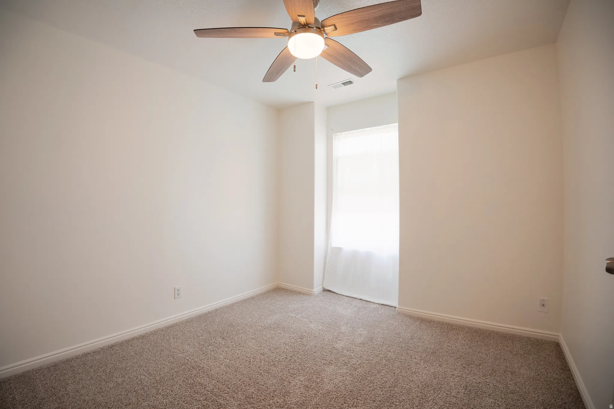 Spare room featuring light carpet and a ceiling fan