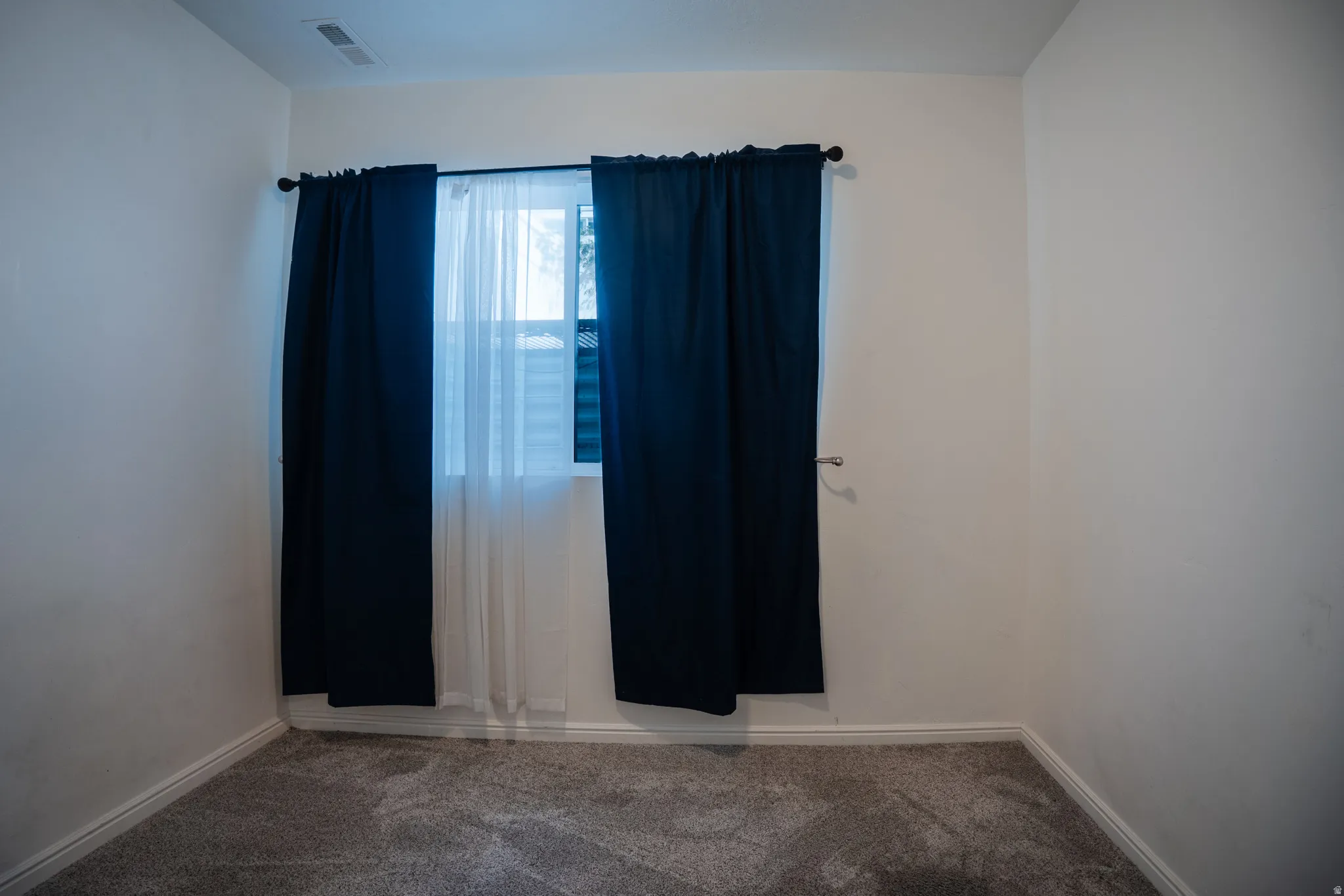 Carpeted empty room featuring baseboards