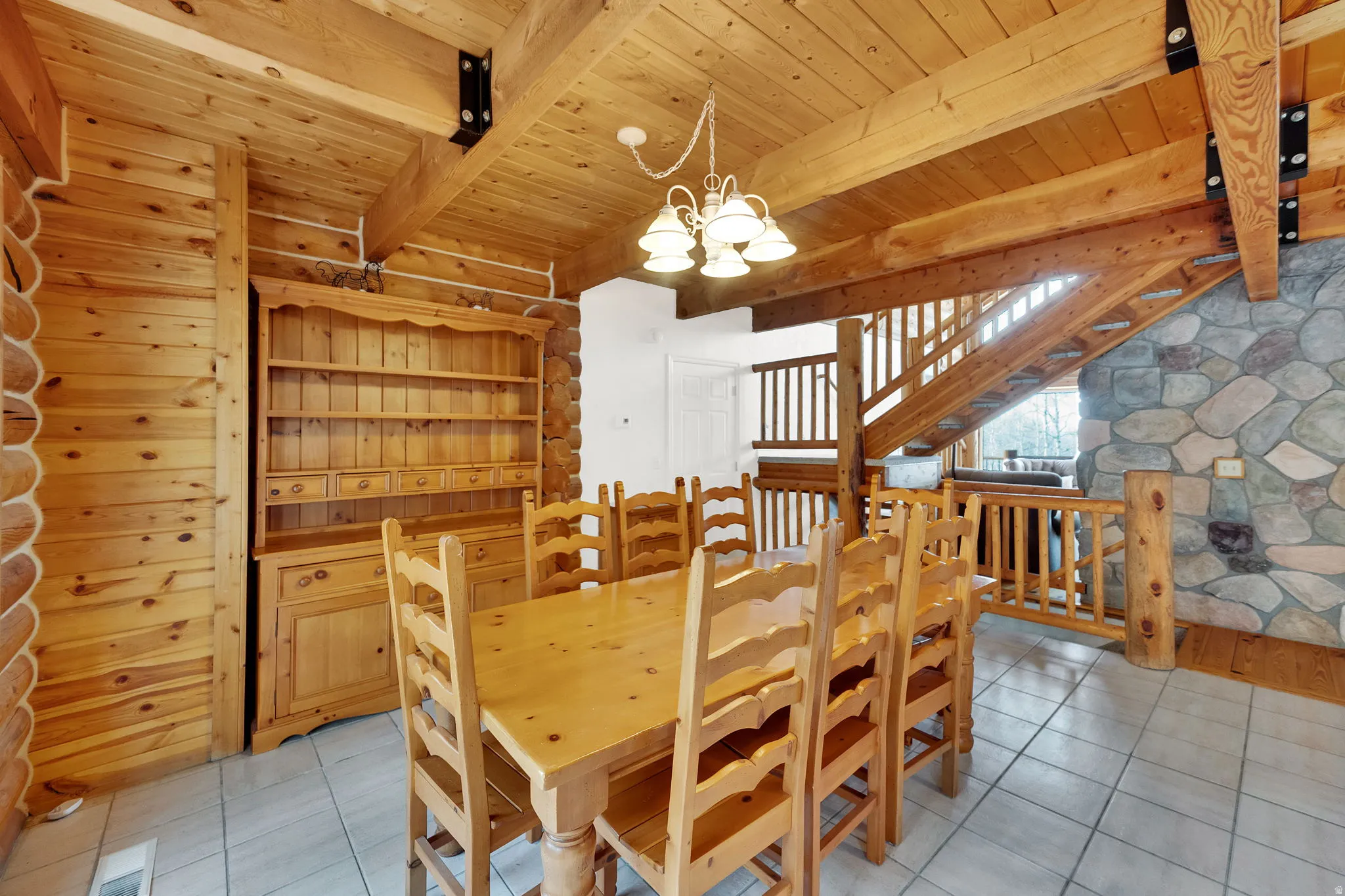 Dining room with a chandelier, light tile patterned flooring, and a wood ceiling with exposed beams