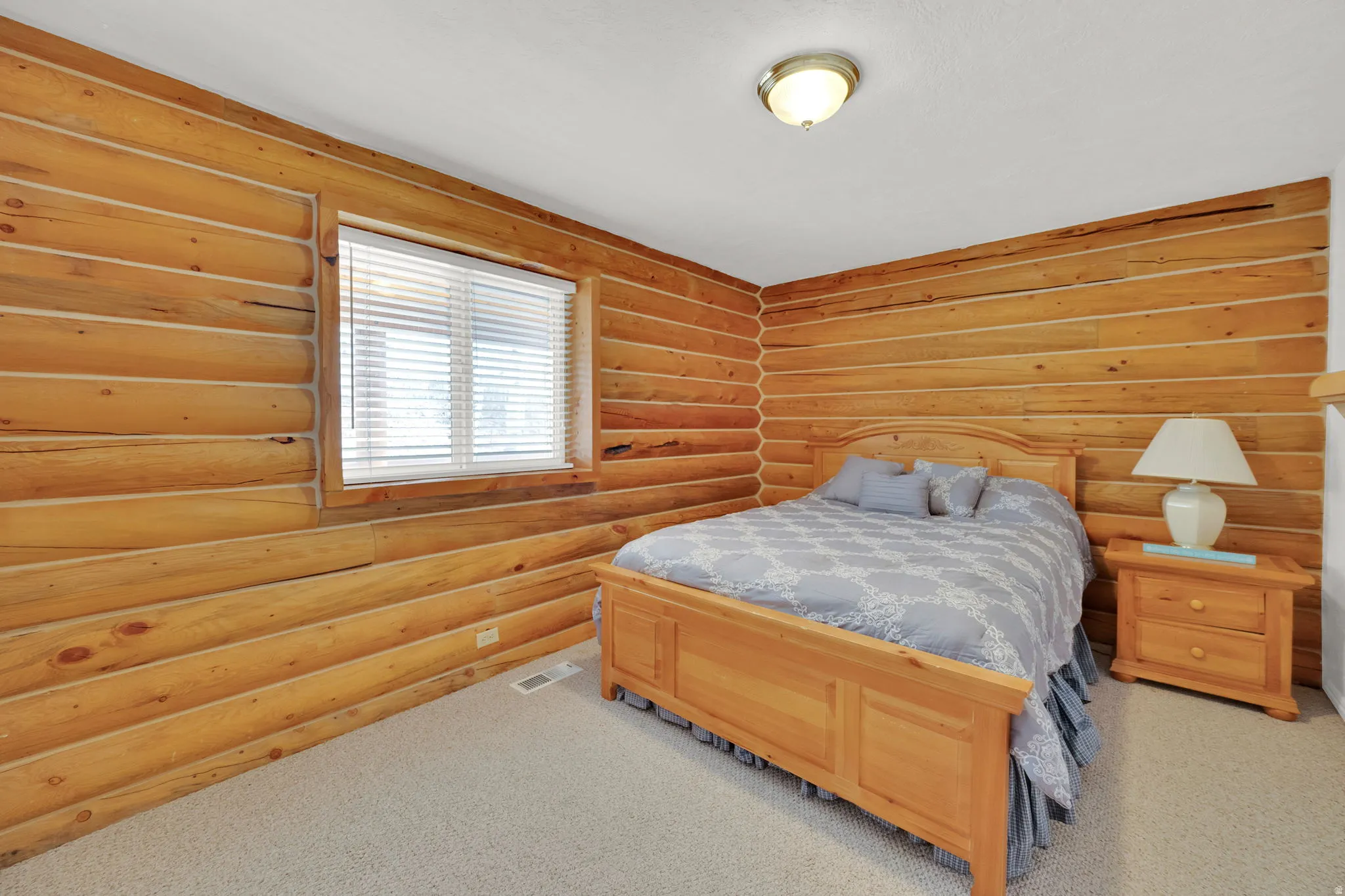 Bedroom with log walls and carpet