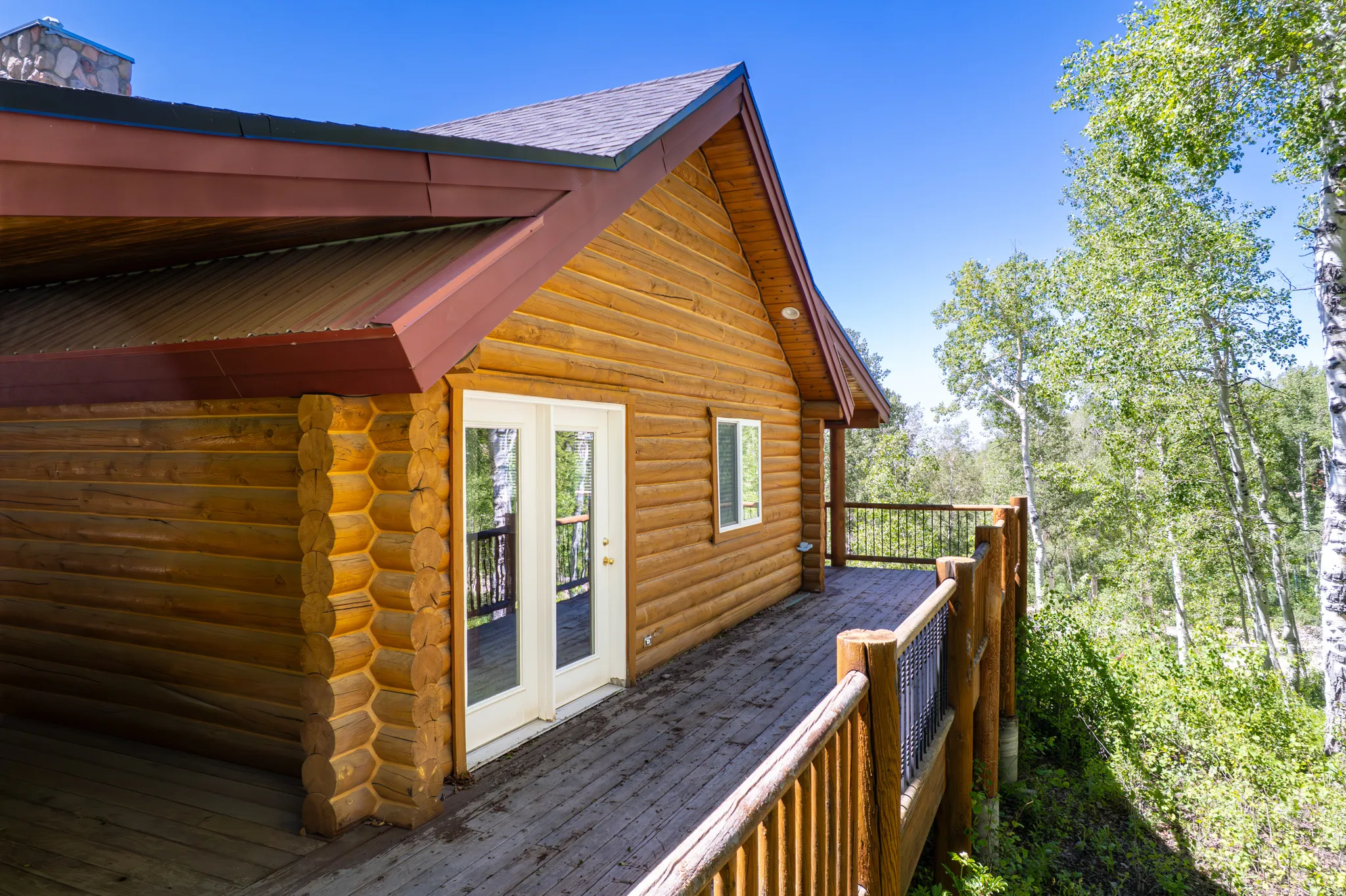 Log-style exterior with an expansive wooden deck featuring a wood railing and dark metal infill