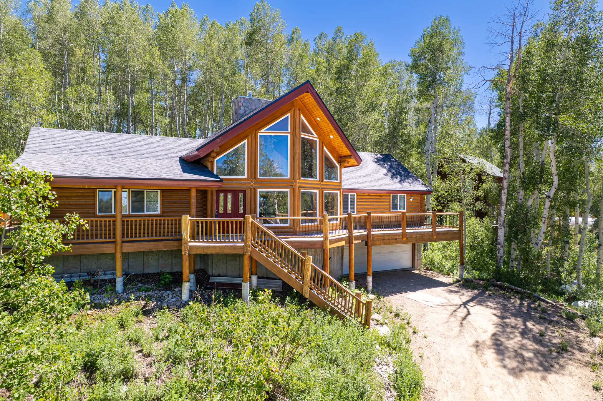 Wood-sided residence featuring a prominent gable roofline and a multi-level deck