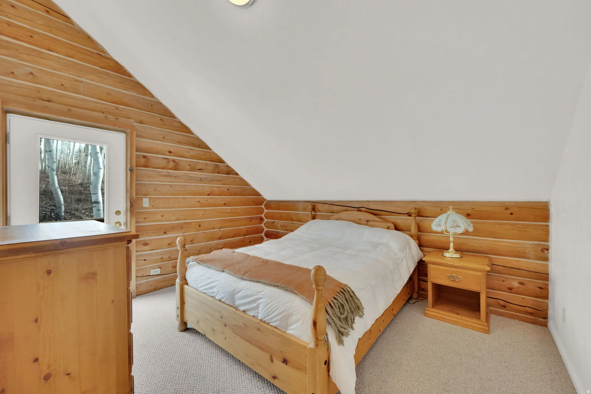 Bedroom featuring rustic walls, light carpet, and vaulted ceiling