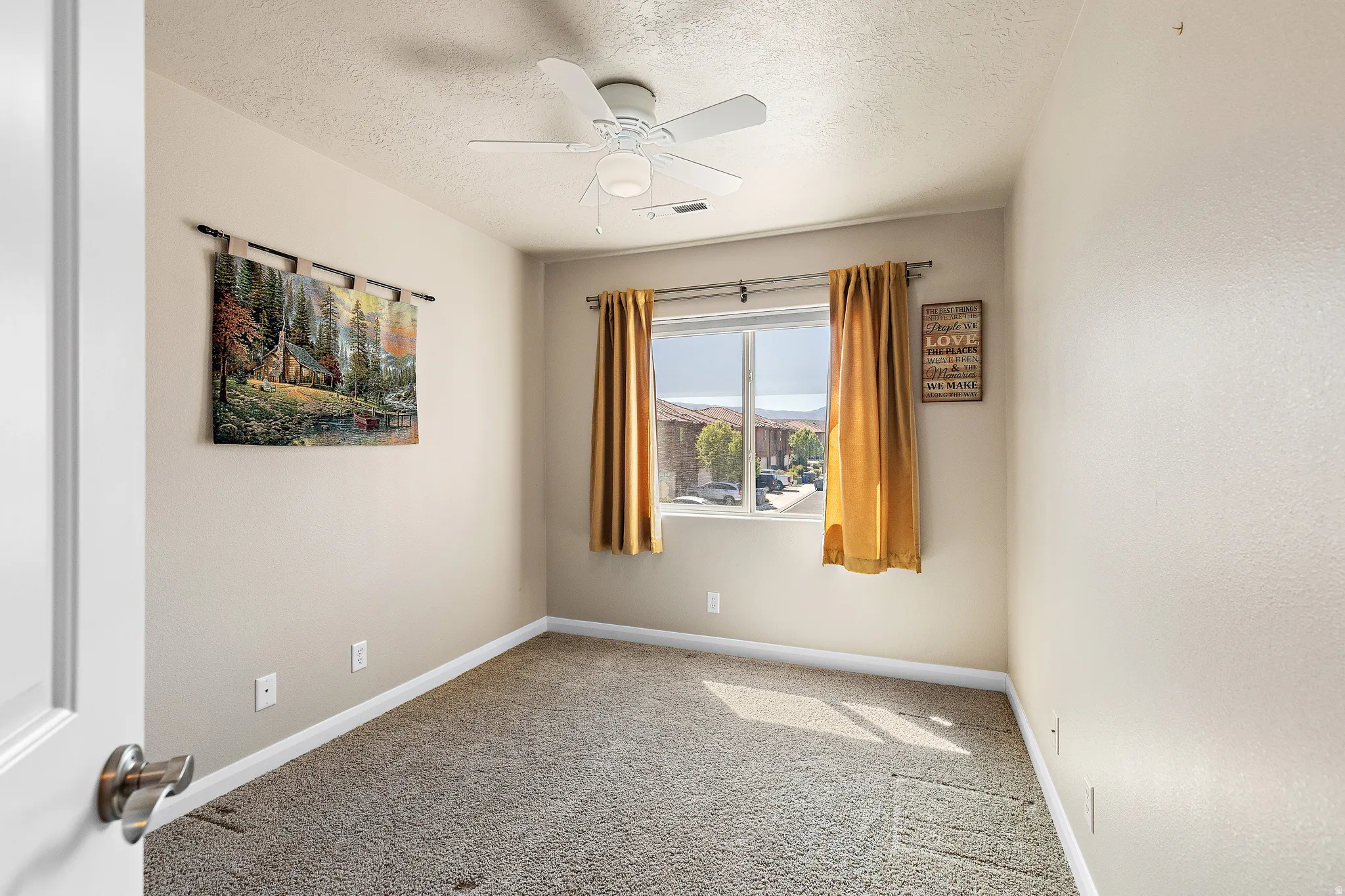 Unfurnished room featuring a textured ceiling, ceiling fan, and light carpet