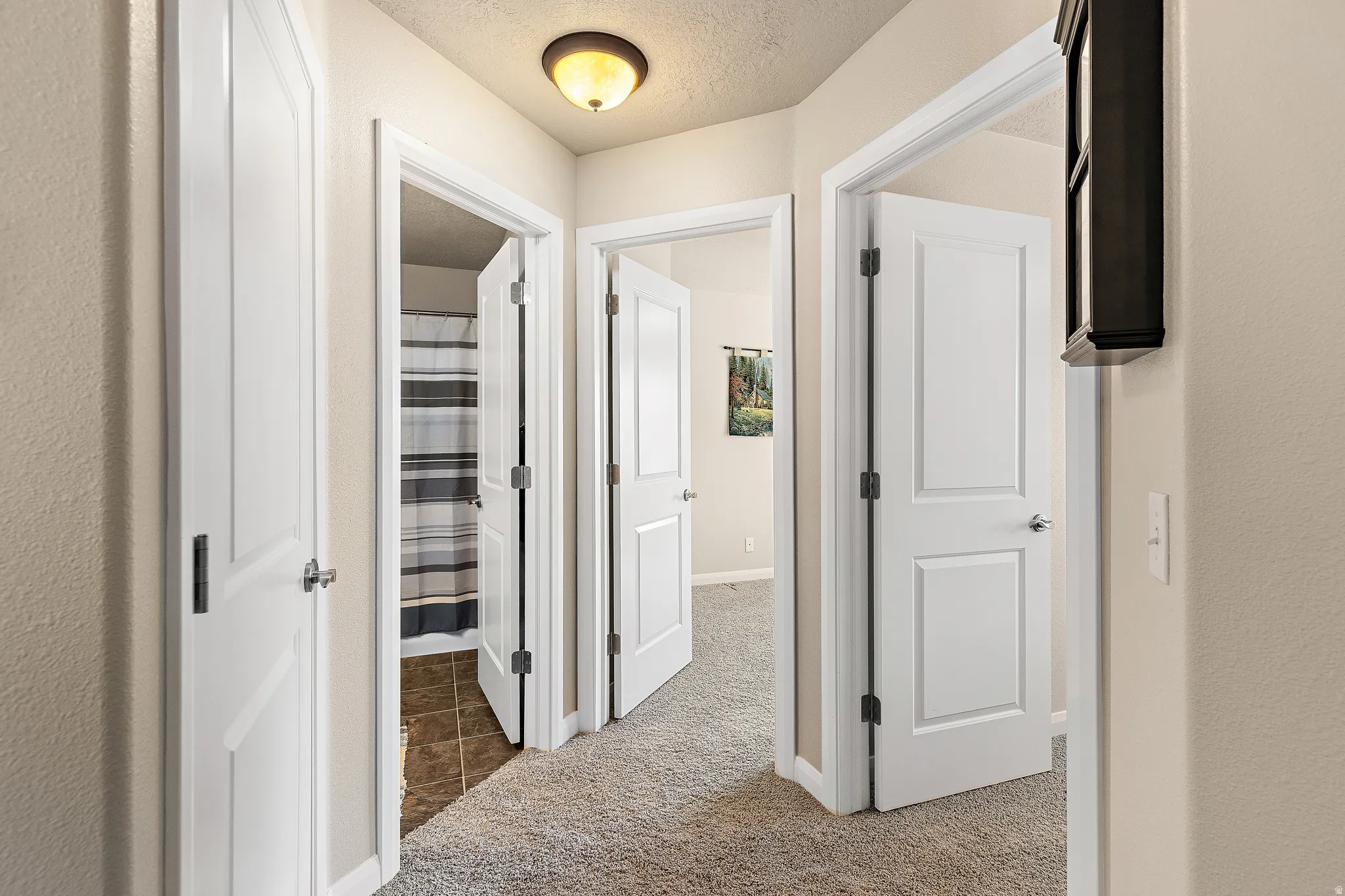 Hallway with a textured ceiling and light colored carpet