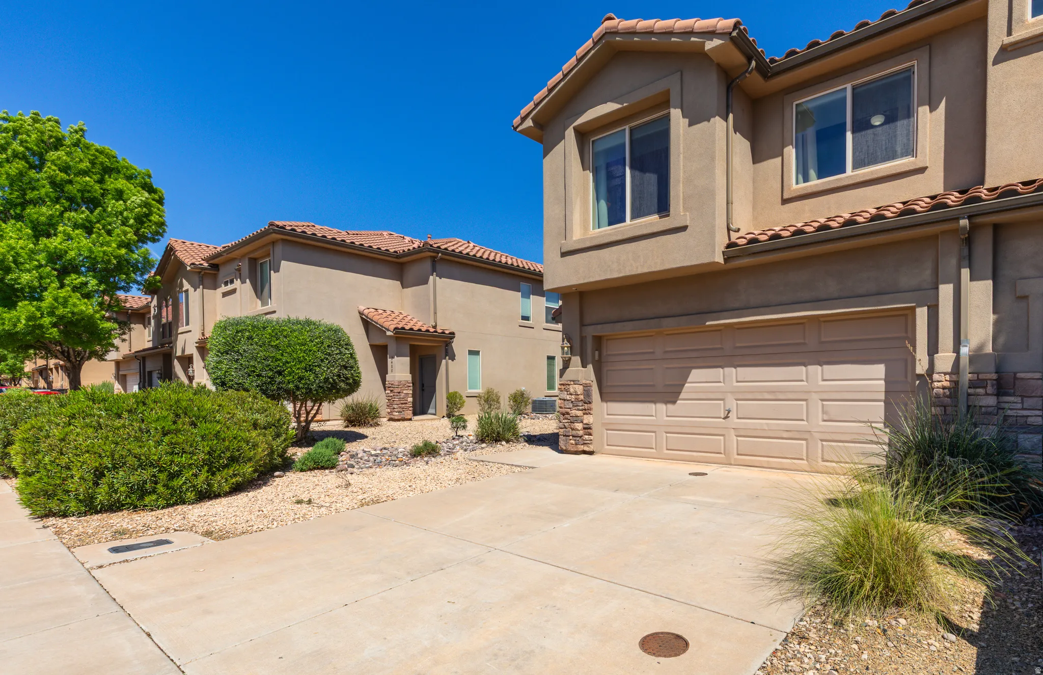 Mediterranean / spanish-style house with an attached garage, a tile roof, stucco siding, and concrete driveway