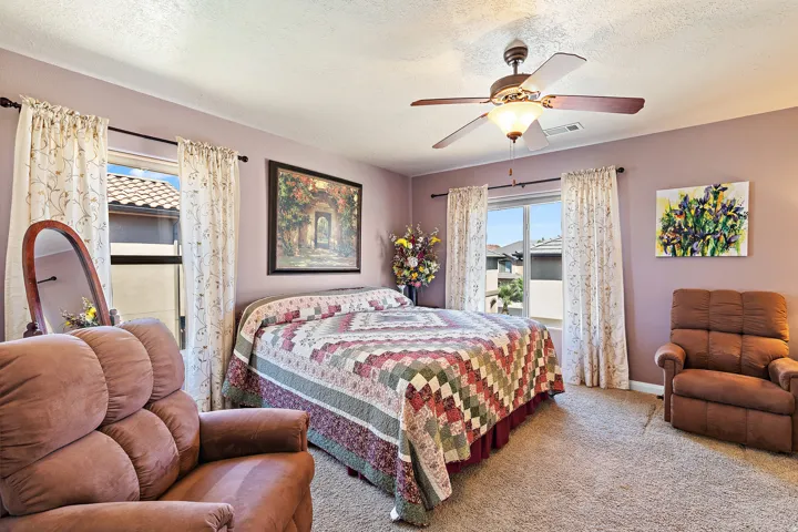 Carpeted bedroom featuring a ceiling fan and a textured ceiling