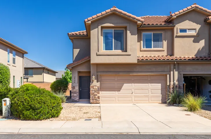 Mediterranean / spanish-style house with an attached garage, stucco siding, driveway, and stone siding
