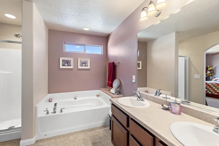 Bathroom with a shower stall, ensuite bathroom, double vanity, a textured ceiling, and a garden tub